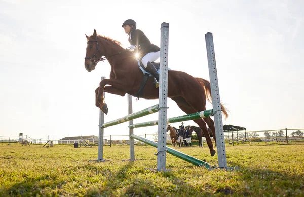 Ao montar um cavalo, pedimos a liberdade emprestada. Tiro de um jovem cavaleiro pulando sobre um obstáculo em seu cavalo. — Fotografia de Stock