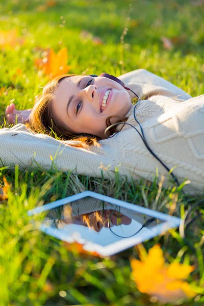 Hon älskar sina låtar. En attraktiv ung kvinna som lyssnar på musik på sin digitala surfplatta utomhus. — Stockfoto