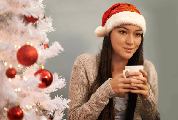 Dricka kakao och tänka på julen. Beskuren bild av en attraktiv ung kvinna njuter av en varm drink på julafton. — Stockfoto