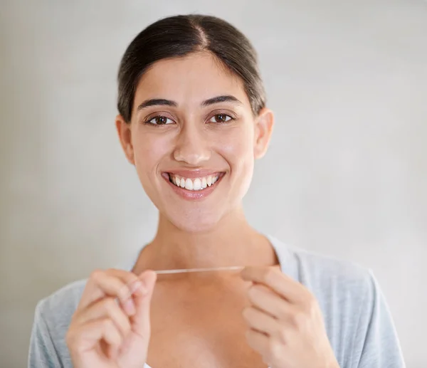 El uso regular de hilo dental mantiene mi sonrisa perfecta. Retrato de una joven atractiva usando hilo dental. — Foto de Stock