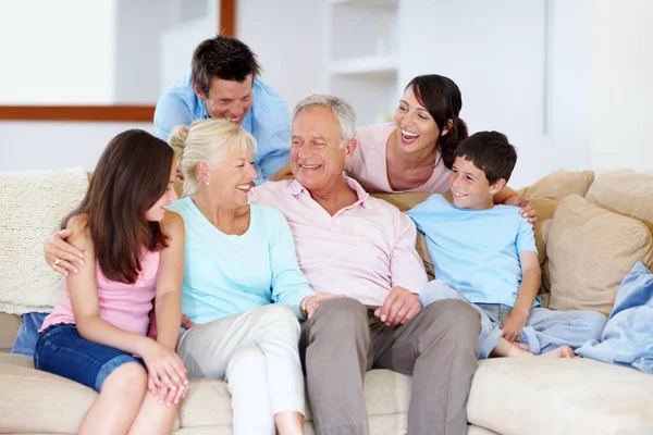 Gostando de piadas de avós juntos. Uma família amorosa rindo em um sofá lounge juntos. — Fotografia de Stock