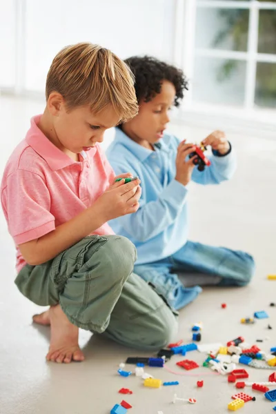 ¿Cómo encajan estas piezas? Dos jóvenes lindos jugando con bloques de construcción en la flor. — Foto de Stock