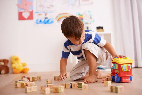 遊びと学び。彼の部屋に彼の建物のブロックとおもちゃのトラックで遊んでいる男の子のショット. — ストック写真