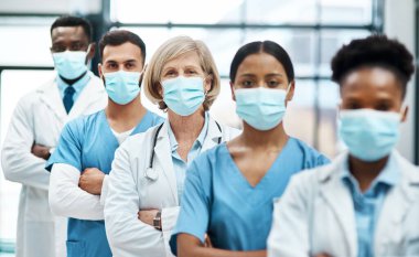 Salgın sırasında hastalarla cephede çalışmak. Hastanede yan yana dururken yüz maskesi takan bir grup tıp doktorunun portresi..