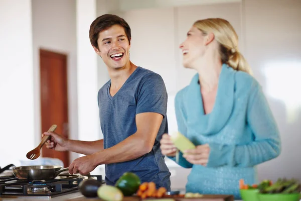 Breng alles op smaak met liefde. Shot van een gelukkig jong koppel koken een maaltijd samen thuis. — Stockfoto