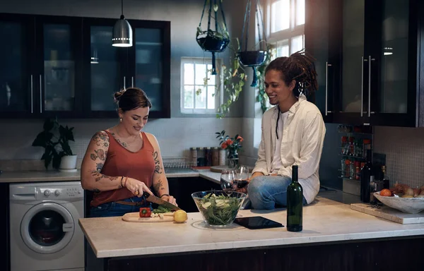 A preparar uma ceia saudável. Tiro de um jovem casal de ligação na cozinha enquanto prepara uma salada. — Fotografia de Stock