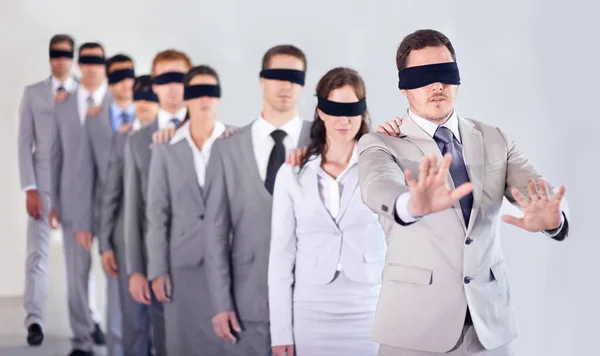 Liderazgo ciego. Una fila de empresarios vendados siguiendo a un líder vendado. —  Fotos de Stock