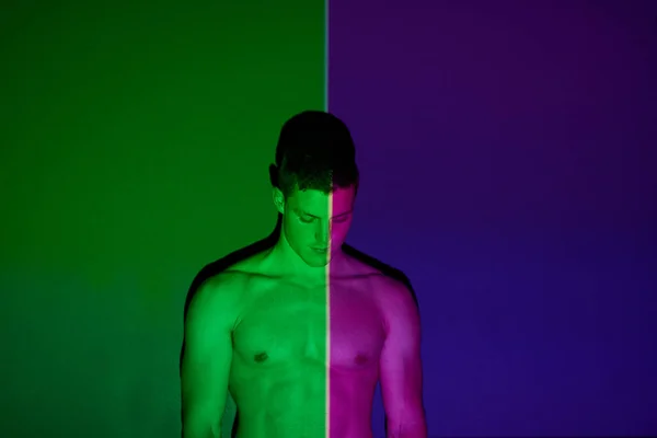 二つの側面があります。抽象的な照明に対してポーズをとる若い男のスタジオショット. — ストック写真