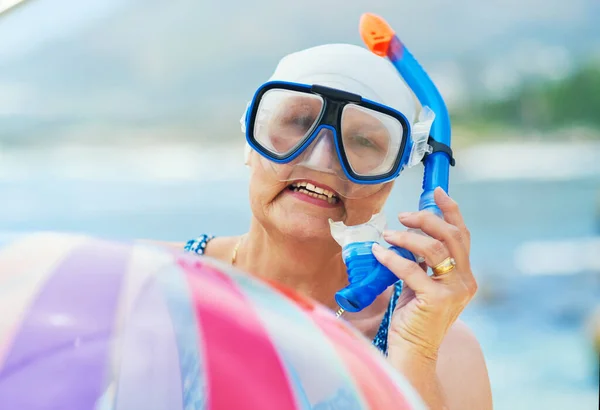 Mijn innerlijke kind laat nooit een snorkelkans liggen. Shot van een volwassen vrouw dragen snorkel gear en het houden van een opblaasbare bal tijdens een dag op het strand. — Stockfoto