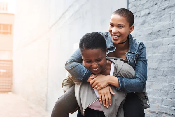 Portarti nel cuore e nello spirito. Girato di una giovane donna che ne portava un'altra sulla schiena mentre rideva in città. — Foto Stock