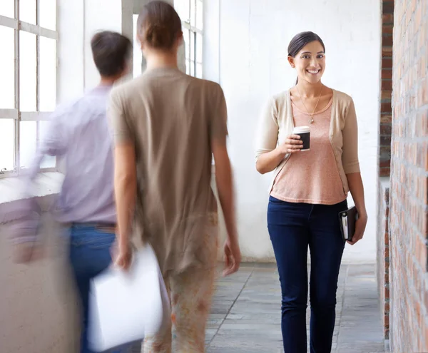 Apenas a tua manhã normal no escritório de design... Tiro de uma mulher caminhando pelo corredor de seu local de trabalho com uma xícara de café na mão. — Fotografia de Stock