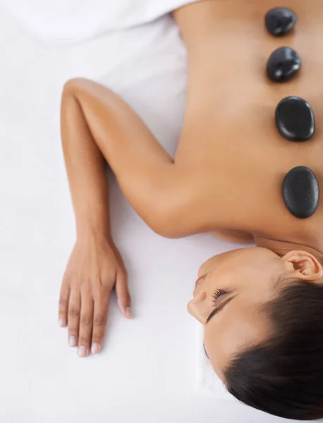 Première étape pour une relaxation totale. Tourné o une jeune femme obtenir un traitement de roche chaude dans un spa. — Photo