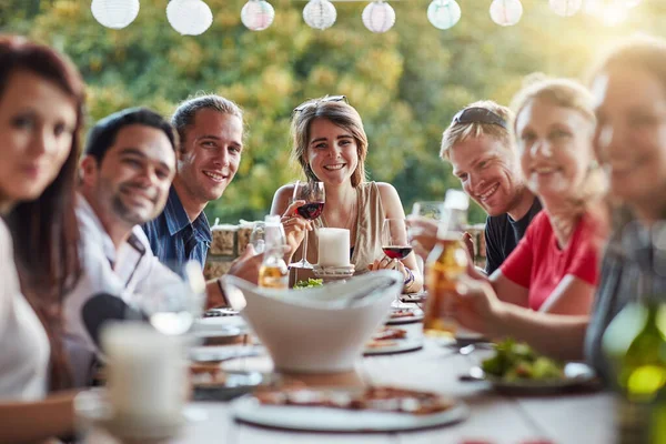 Nada por boas vibrações à nossa mesa. Retrato de um grupo de jovens amigos felizes compartilhando uma refeição em um jantar no quintal. — Fotografia de Stock