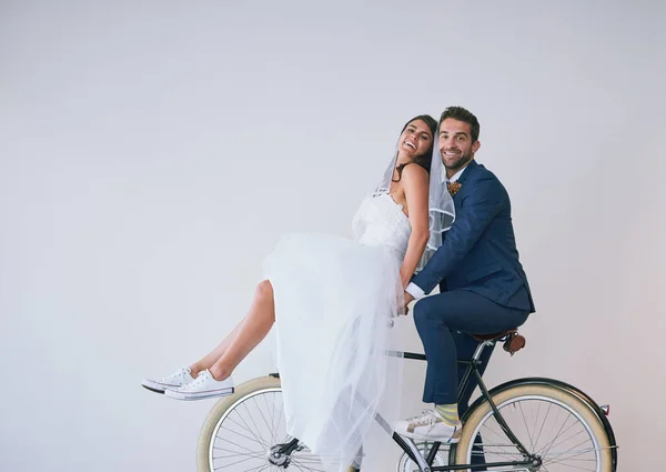 Arrivée dans le style. Plan studio d'un jeune couple nouvellement marié en vélo ensemble sur un fond gris. — Photo