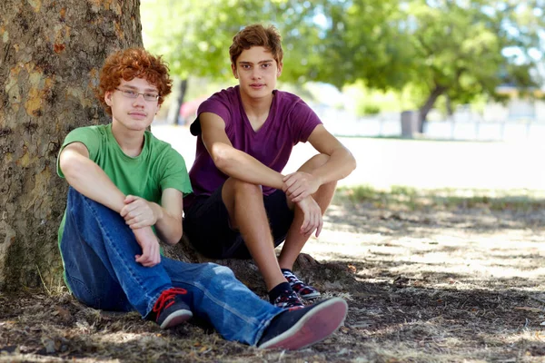 Ловлю тень в жаркий день. Фотография двух подростков, отдыхающих в тени дерева в парке. — стоковое фото