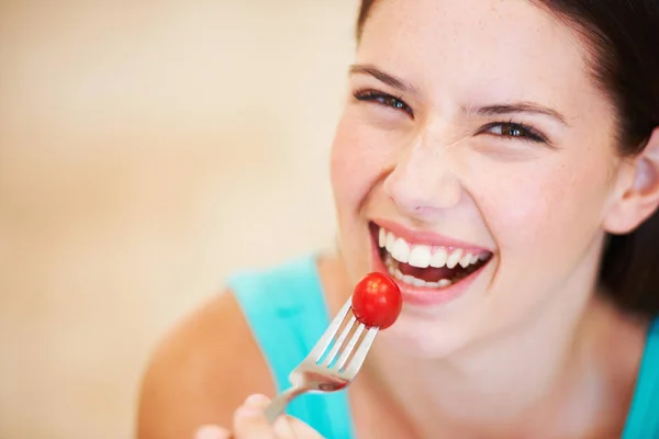 Наслаждаюсь детским помидором. Портрет красивой молодой женщины, поедающей помидор. — стоковое фото