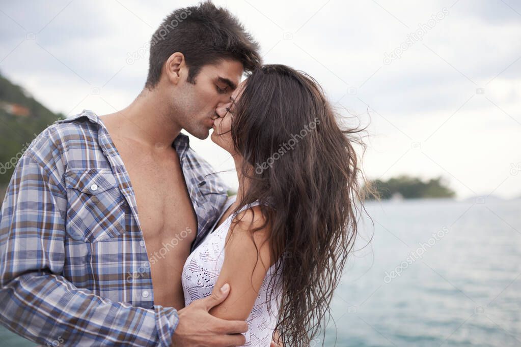 Taking their love outside. Shot of an intimate young couple enjoying a kiss by the waters edge.