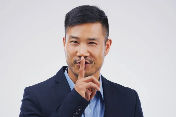 Nazywasz to umową o nieujawnianiu informacji. Portret przystojnego biznesmena pozującego z palcem na ustach na szarym tle. — Zdjęcie stockowe