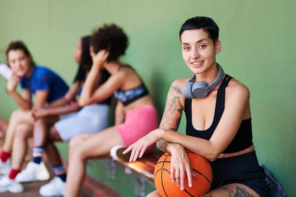 Lek alltid av hela ditt hjärta. Porträtt av en sportig ung kvinna som tar en paus med sina vänner efter en omgång basket. — Stockfoto
