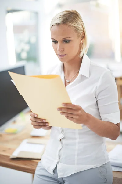 Examen des rapports trimestriels. Une femme d'affaires lisant un document dans son bureau. — Photo