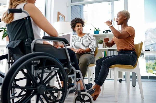Ils sont pleins d'idées brillantes. Prise de vue d'une femme d'affaires handicapée assise avec des collègues au bureau. — Photo