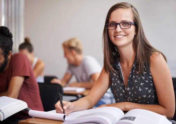 Er is niets belangrijker voor mij dan onderwijs. Een aantrekkelijke jonge student van de universiteit zit in een klaslokaal met een leerboek voor haar. — Stockfoto