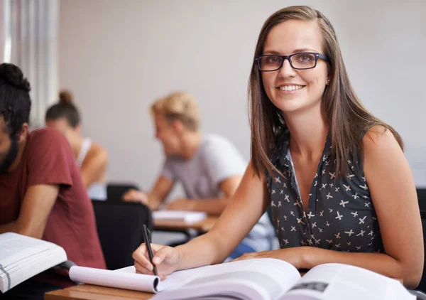 Não há nada mais importante para mim do que a educação. Uma jovem e atraente estudante do colégio sentada em uma sala de aula com um livro na frente dela. — Fotografia de Stock