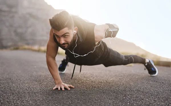 Verdraag elke uitdaging en het zal je veranderen. Opname van een sportieve jongeman die push-ups doet terwijl hij buiten traint. — Stockfoto