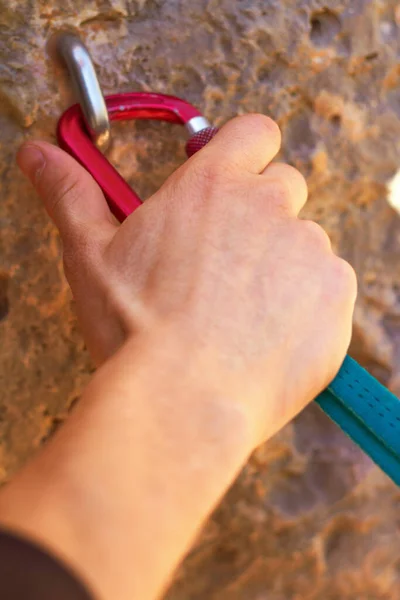 Getting a stable grip. Closeup of a climbers hands clipping a quickdraw onto a hook bolted into a rock. — Stock Photo, Image
