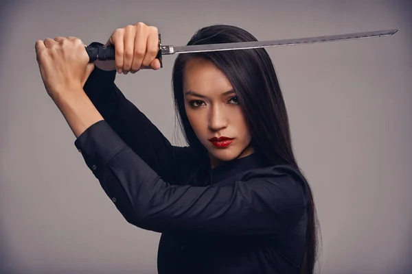 Ninjaların yolu. Dövüş sanatları kıyafeti giymiş, elinde samuray kılıcı olan güzel bir kadının stüdyo portresi.. — Stok fotoğraf