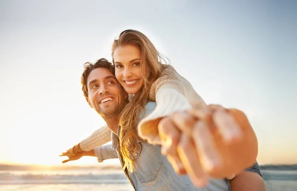 Ihre Liebe feiern. Ein glückseliges junges Paar feiert seine Liebe gemeinsam am Strand. — Stockfoto