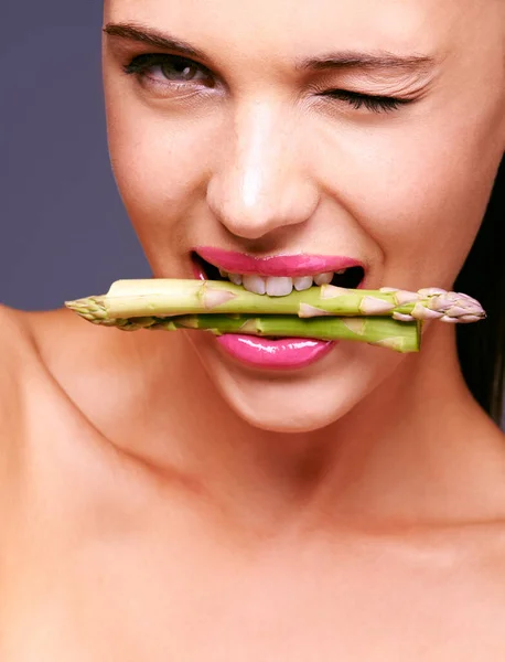 Flirtowanie z jedzeniem. Portret kobiety gryzącej szparagi w studiu. — Zdjęcie stockowe
