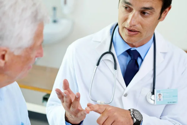 A certificar-se que o paciente compreende... Tiro de um jovem médico bonito explicando a situação a um paciente sênior. — Fotografia de Stock