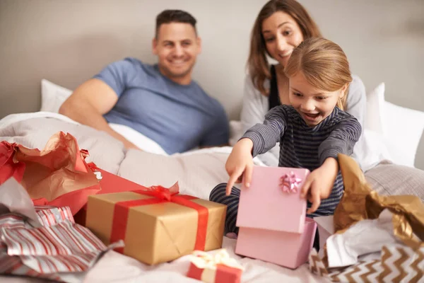 Hű, köszi, anya és apa. Egy kislányról, aki ajándékokat bontott fel az ágyban, miközben a szülei nézték,. — Stock Fotó