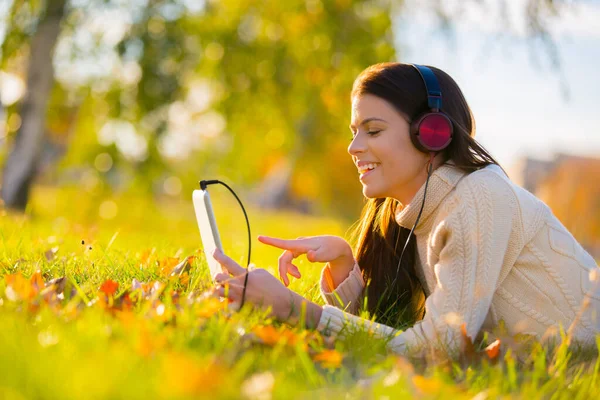 Elle adore ses airs. Une jeune femme séduisante écoutant de la musique sur sa tablette numérique en plein air. — Photo