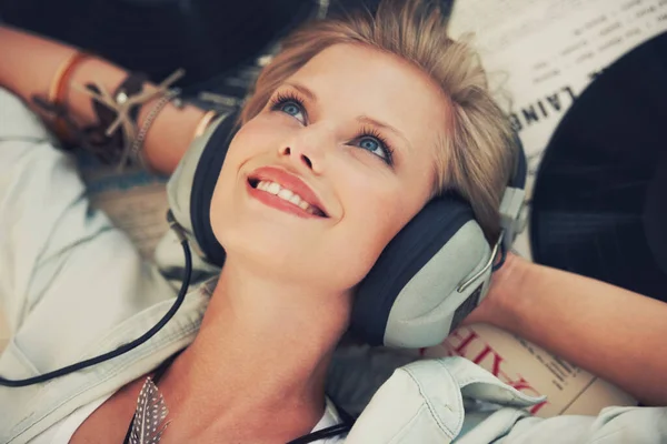 La buena música no tiene fecha de caducidad. Cortada la foto de una hermosa joven escuchando música mientras yacía en el interior. —  Fotos de Stock