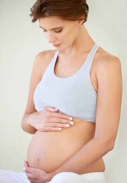 Grandes expectativas. Uma bela jovem grávida olhando para a barriga nua. — Fotografia de Stock