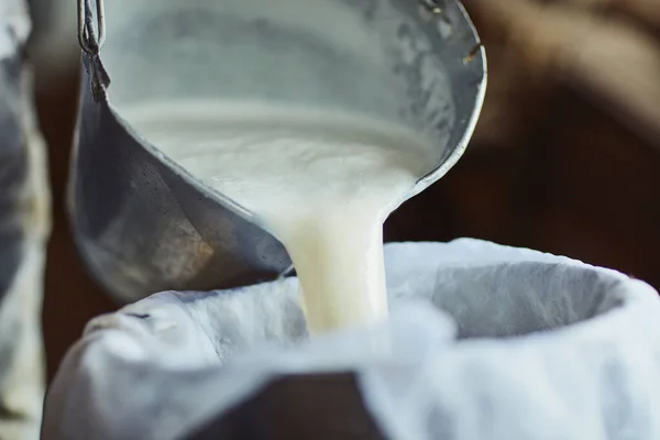Шаги к приготовлению сыра. Обрезанный снимок мужчины-фермера, заливающего необработанное молоко в контейнер в сарае. — стоковое фото