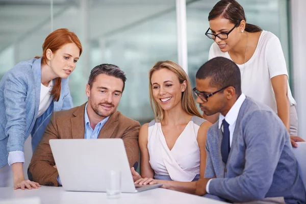 A juntar as cabeças. Tiro de um grupo diversificado de empresários usando um laptop juntos. — Fotografia de Stock