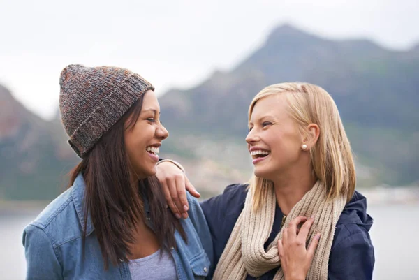 Zahřívá den přátelstvím a smíchem. Dvě šťastné mladé ženy se usmívají na pláži. — Stock fotografie
