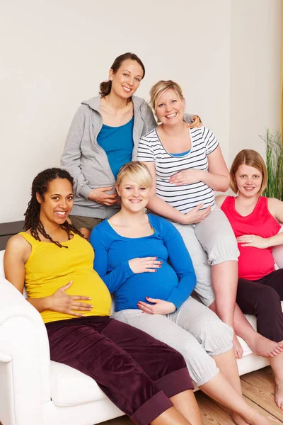 Non possiamo aspettare il grande giorno. Un gruppo di donne incinte multietniche sedute su un divano e sorridenti alla telecamera. — Foto Stock