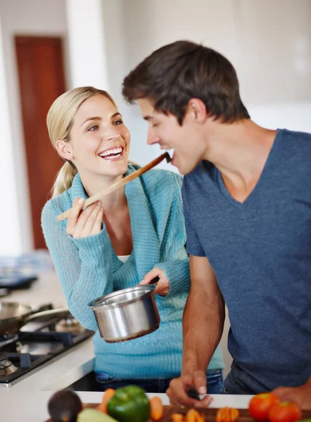 La vida es deliciosa. Foto de una hermosa joven mujer dando a su marido un sabor de su cocina. — Foto de Stock