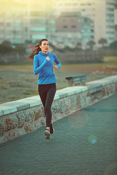 Correr é uma forma de relaxamento. Tiro de uma jovem esportiva correndo no passeio. — Fotografia de Stock