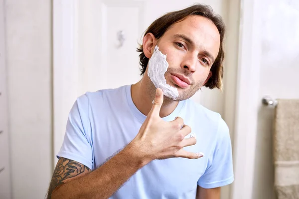 I like this consistency so far. Shot of a young man applying shaving foam to his face. — Stock Photo, Image