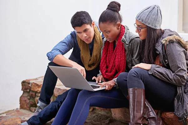 Druk met hun laatste huiswerk. Foto van een groep universiteitsstudenten die een laptop gebruiken terwijl ze op de campus zitten. — Stockfoto