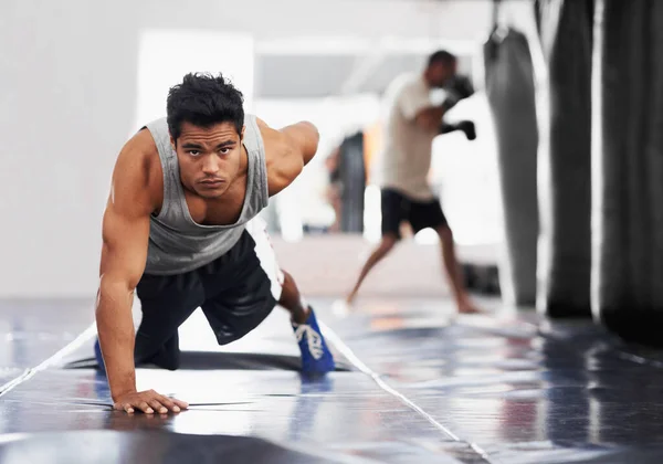 Pura fuerza feroz. Retrato de un joven boxeador enfocado haciendo flexiones en el gimnasio. — Foto de Stock