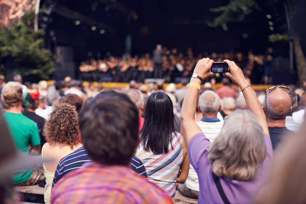 Malé kamery zachycují skvělé vzpomínky. Snímek člověka v davu, který drží fotoaparát a fotografuje klasický koncert. — Stock fotografie