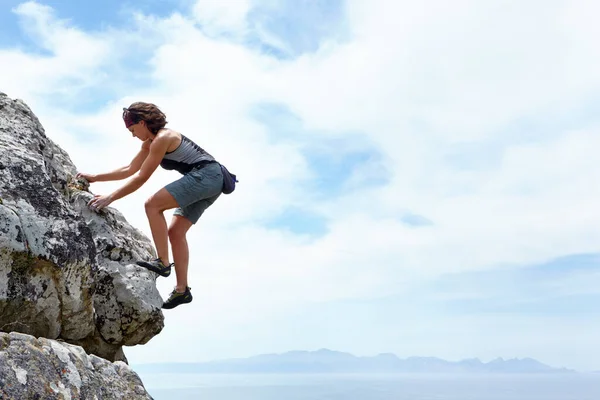 Δεν υπάρχει βουνό πολύ ψηλά. Μια γυναίκα σκαρφαλώνει σε ένα βράχο μια ηλιόλουστη μέρα. — Φωτογραφία Αρχείου