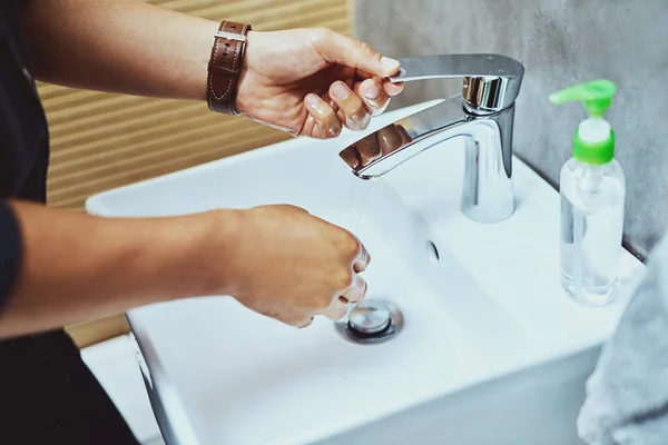 Goede hygiëne begint bij jou. Gehakt schot van een onherkenbare man wassen zijn handen in de badkamer wastafel. — Stockfoto