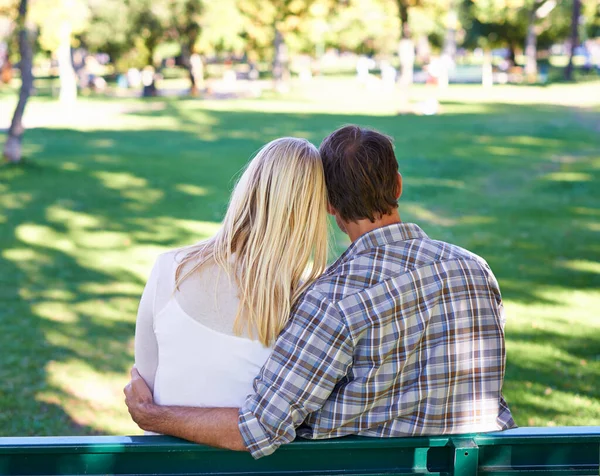 Életben tartani a fiatal szerelmet. Egy kedves fiatal pár visszapillantása, akik egy padon ülnek a parkban.. — Stock Fotó